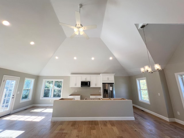 kitchen with light wood finished floors, baseboards, white cabinets, a kitchen island, and stainless steel appliances