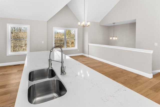 kitchen with a sink, light wood-style flooring, a notable chandelier, and hanging light fixtures