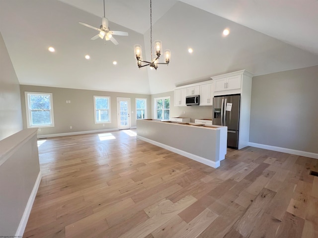 kitchen featuring stainless steel appliances, open floor plan, white cabinetry, and light wood finished floors