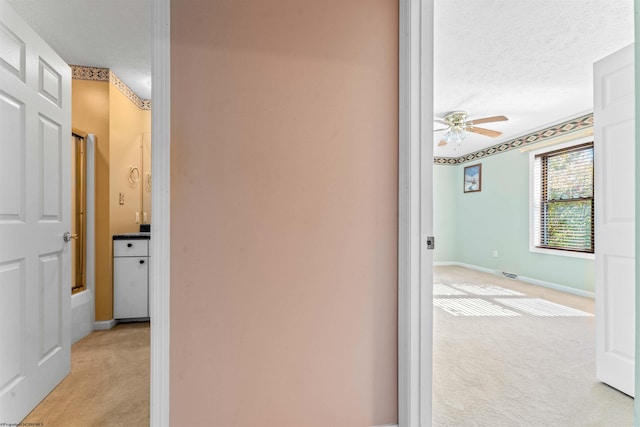 hall with light carpet and a textured ceiling