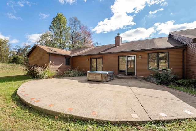 back of property featuring a hot tub and a patio