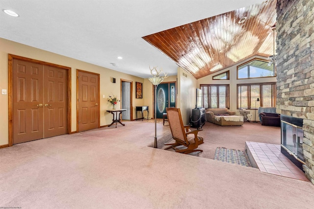 living room with carpet, vaulted ceiling, and a large fireplace