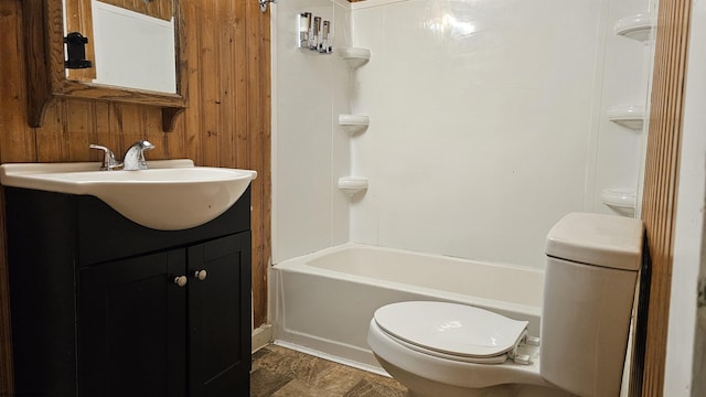 full bath featuring toilet, washtub / shower combination, wood walls, and vanity