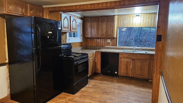 kitchen with light wood finished floors, brown cabinets, a sink, black appliances, and ornamental molding