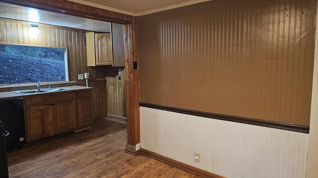 kitchen featuring wood finished floors, ornamental molding, a sink, baseboards, and wooden walls