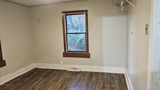spare room featuring crown molding, visible vents, baseboards, and dark wood finished floors