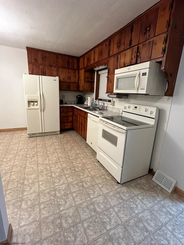 kitchen with sink, a textured ceiling, and white appliances