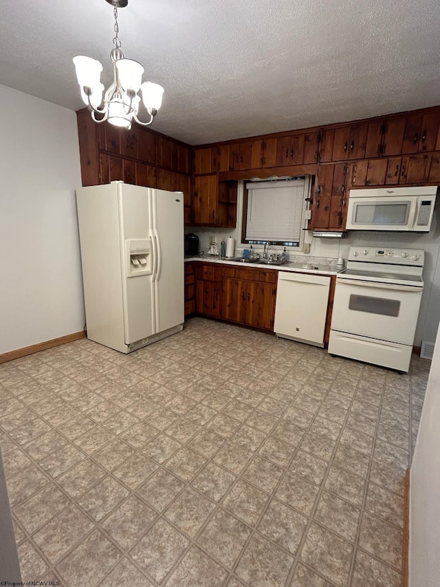 kitchen featuring white appliances, sink, a textured ceiling, decorative light fixtures, and a notable chandelier