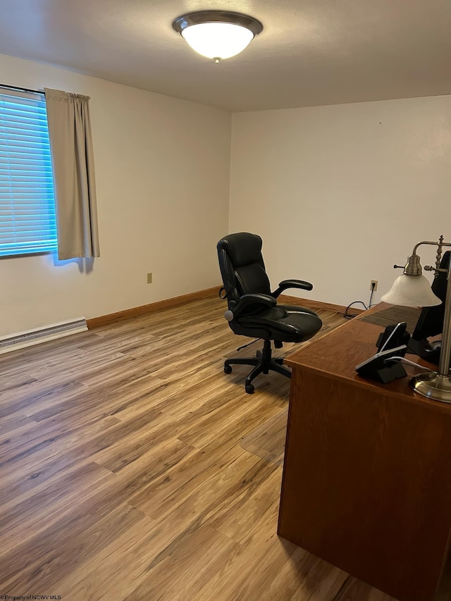 office space with light hardwood / wood-style floors and a baseboard heating unit