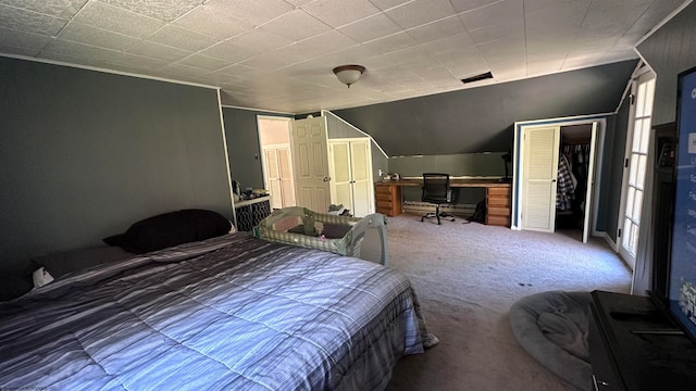 carpeted bedroom with a closet, connected bathroom, and vaulted ceiling