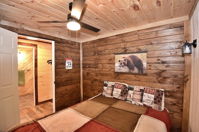 bedroom featuring hardwood / wood-style floors, wood ceiling, wooden walls, and ceiling fan