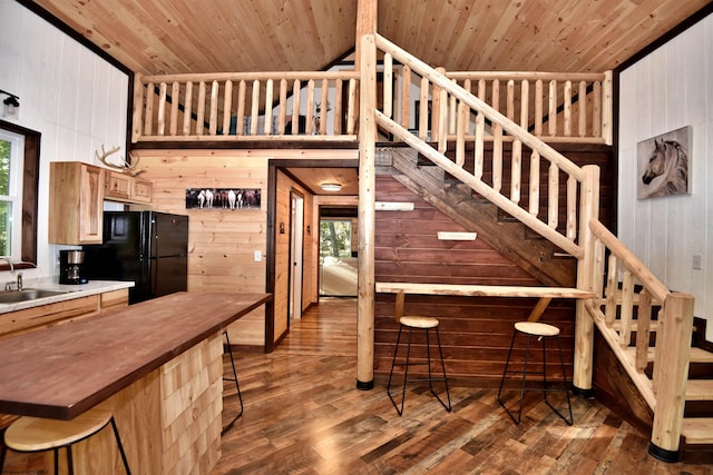 kitchen featuring wood walls, wooden ceiling, dark hardwood / wood-style floors, and black refrigerator