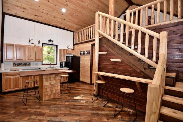 kitchen with a breakfast bar area, wooden ceiling, dark hardwood / wood-style floors, black refrigerator, and sink