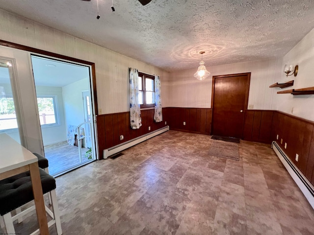 unfurnished room featuring a baseboard radiator, a textured ceiling, and a healthy amount of sunlight