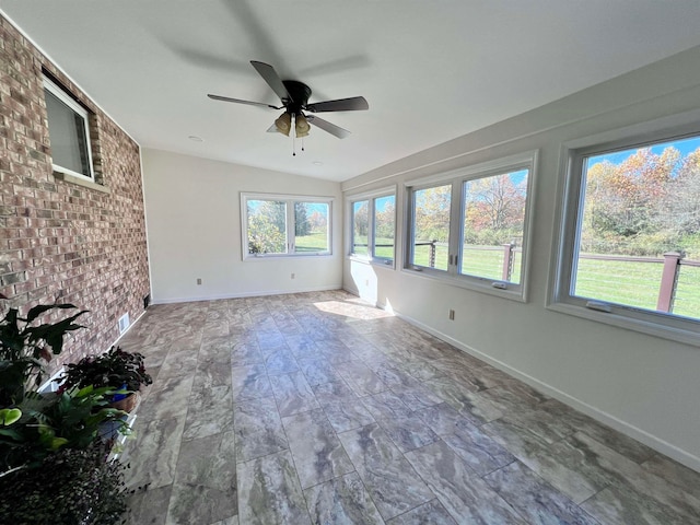 unfurnished sunroom with vaulted ceiling, ceiling fan, and plenty of natural light