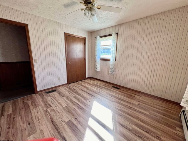 unfurnished bedroom featuring hardwood / wood-style floors, a textured ceiling, and ceiling fan