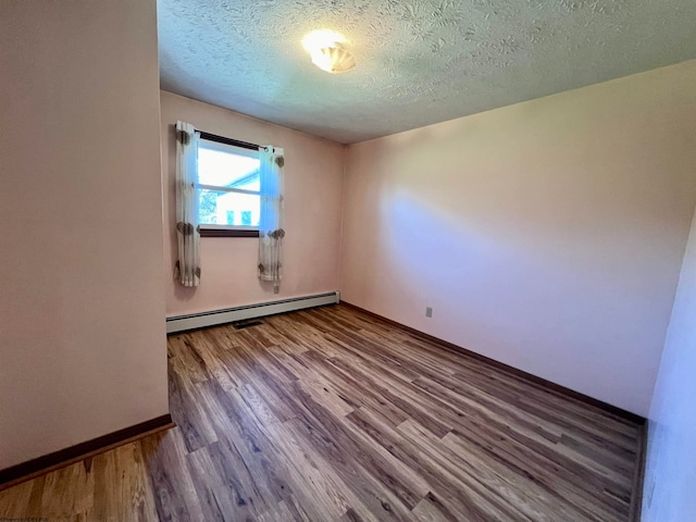 unfurnished room with baseboard heating, a textured ceiling, and wood-type flooring