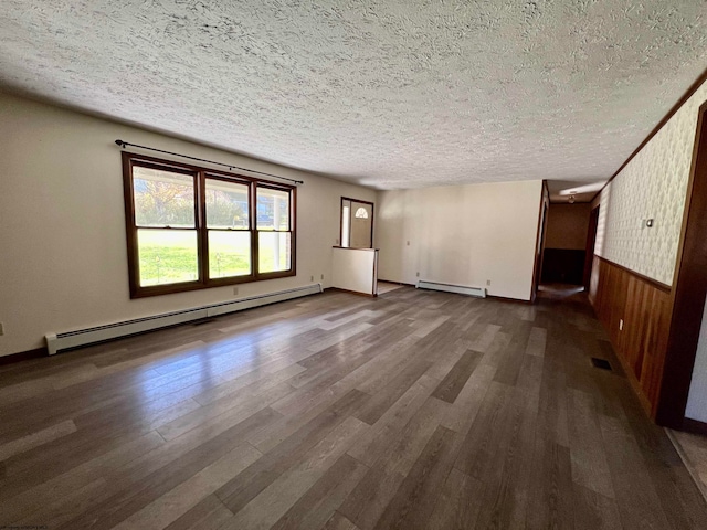 unfurnished living room with dark wood-type flooring, a baseboard heating unit, and wooden walls