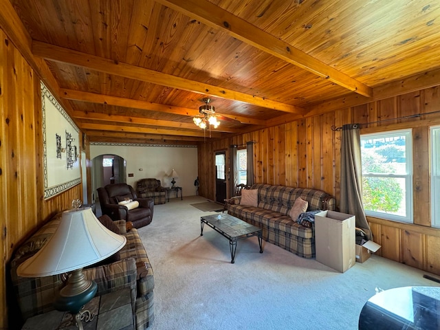 living room featuring ceiling fan, wooden ceiling, wooden walls, beam ceiling, and carpet