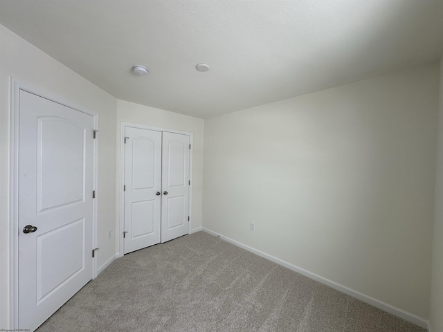 unfurnished bedroom with light colored carpet and a closet