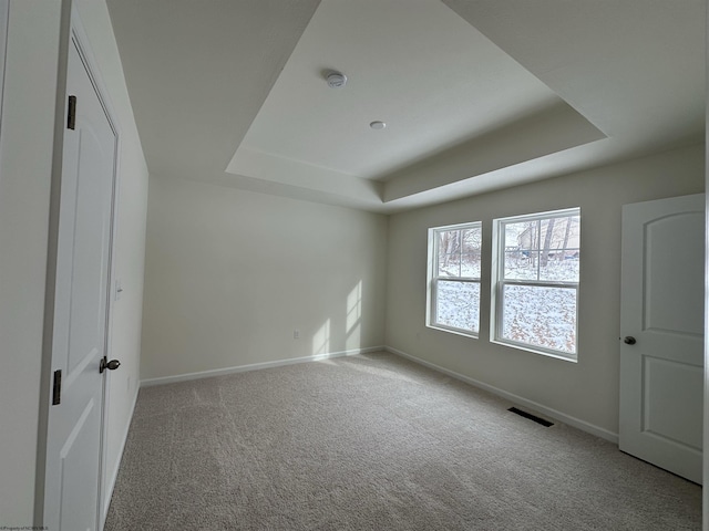 unfurnished bedroom featuring light carpet and a tray ceiling