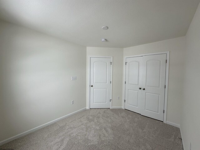 unfurnished bedroom featuring light carpet and a closet