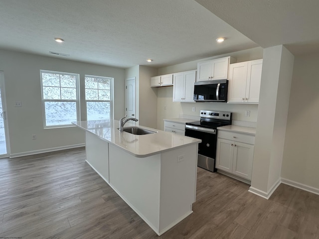 kitchen with appliances with stainless steel finishes, sink, a center island with sink, white cabinets, and light hardwood / wood-style floors