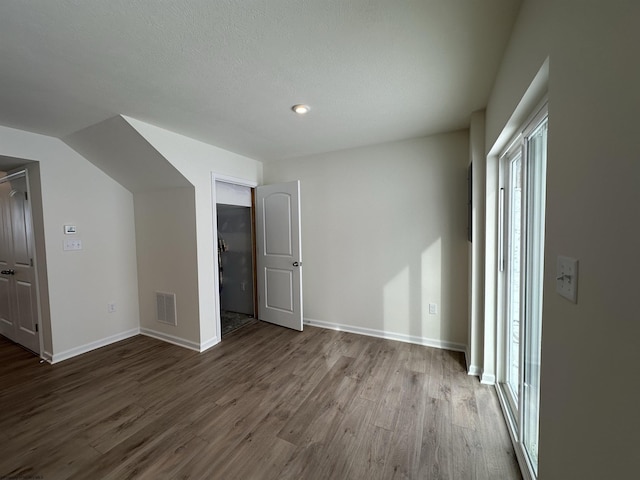 unfurnished bedroom with hardwood / wood-style floors and vaulted ceiling