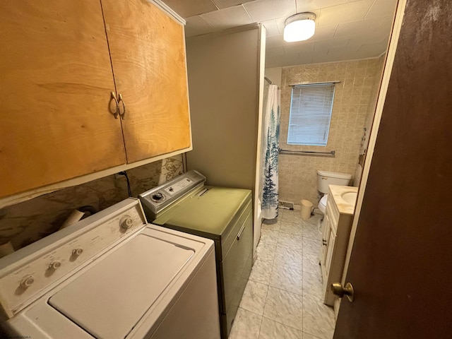 laundry area with independent washer and dryer and tile walls