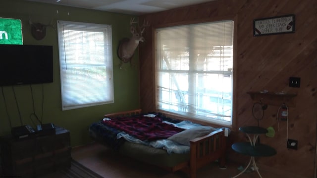 bedroom featuring multiple windows and wooden walls