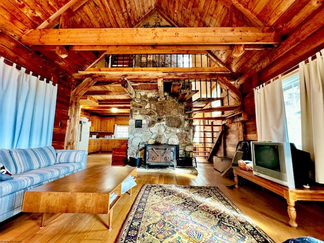 living room with beam ceiling, wood ceiling, light wood-type flooring, and a wood stove