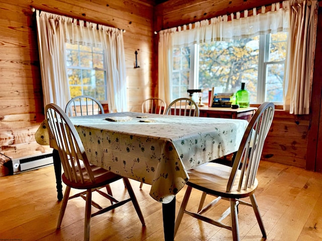 dining area with light hardwood / wood-style floors and wooden walls