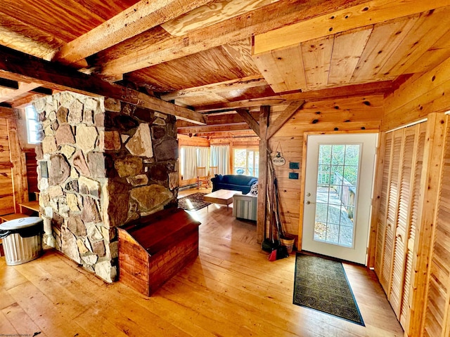 bedroom featuring beam ceiling, wooden walls, light hardwood / wood-style flooring, and wood ceiling