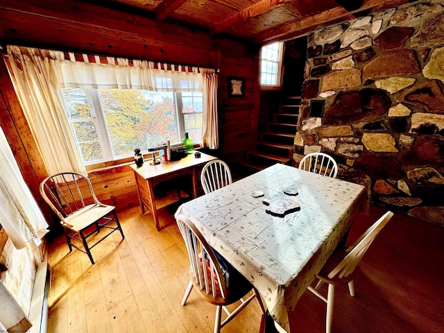 dining room with wood walls, beamed ceiling, wood-type flooring, and wooden ceiling