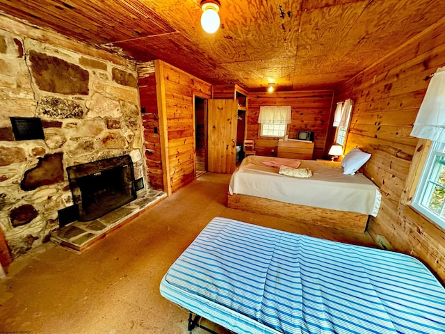 bedroom with wooden walls, wooden ceiling, and a fireplace