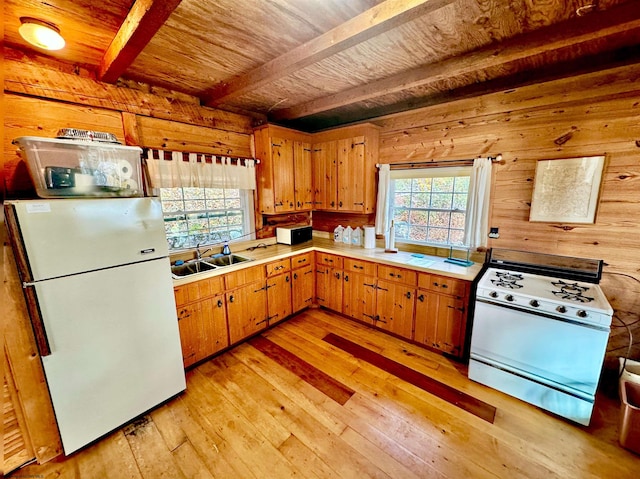 kitchen with white appliances, sink, beamed ceiling, wooden walls, and light hardwood / wood-style flooring