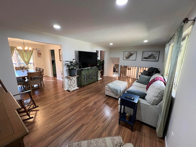 living room featuring a textured ceiling, a chandelier, and dark wood-type flooring