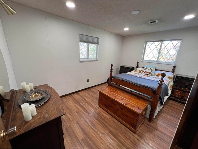 bedroom with hardwood / wood-style floors, multiple windows, and a textured ceiling