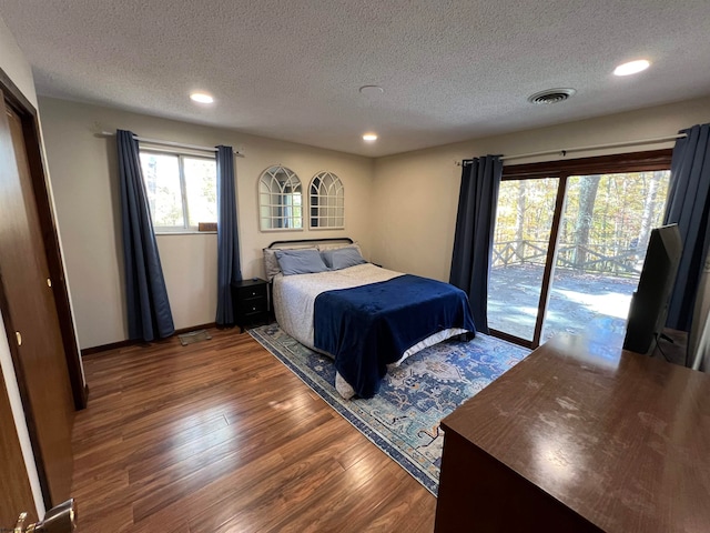 bedroom with dark wood-type flooring, a textured ceiling, and access to exterior