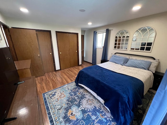 bedroom with multiple closets and hardwood / wood-style floors