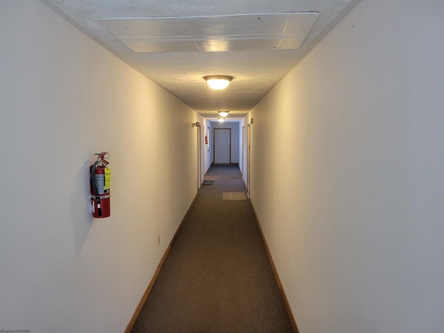 hallway featuring dark colored carpet