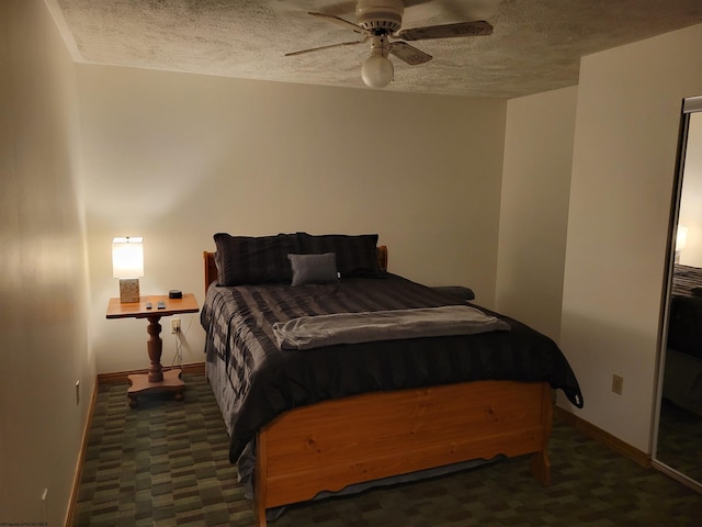 bedroom with ceiling fan, a textured ceiling, and dark colored carpet