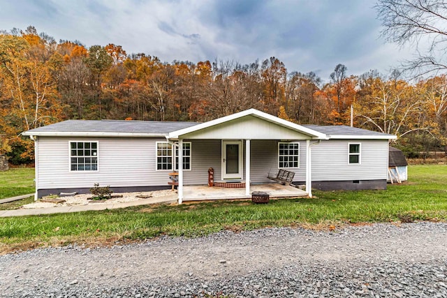 view of front facade featuring covered porch, crawl space, a wooded view, and a front yard