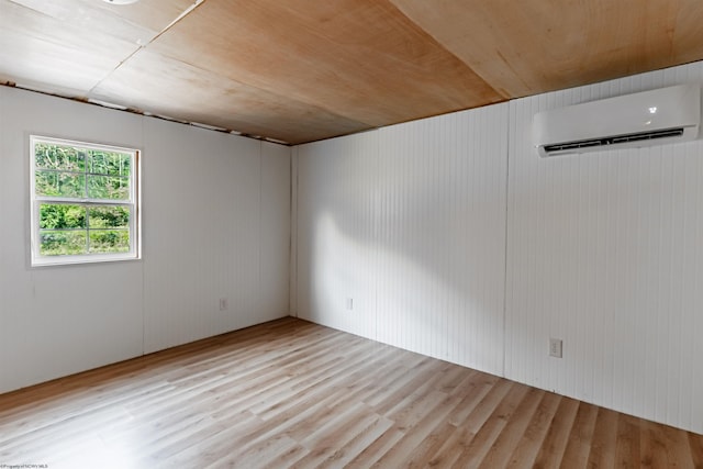 unfurnished room with wood walls, a wall mounted AC, light wood-type flooring, and wooden ceiling