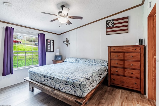 bedroom featuring ceiling fan, crown molding, a textured ceiling, and hardwood / wood-style floors