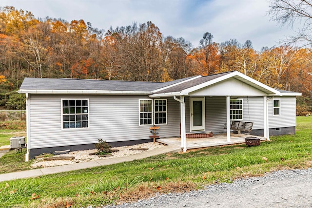 ranch-style home featuring central air condition unit, covered porch, a front yard, and crawl space