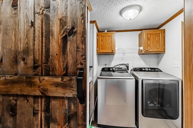 laundry room featuring ornamental molding, cabinet space, a textured ceiling, and washer and clothes dryer