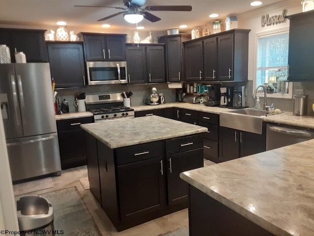 kitchen featuring decorative backsplash, ceiling fan, stainless steel appliances, sink, and a center island