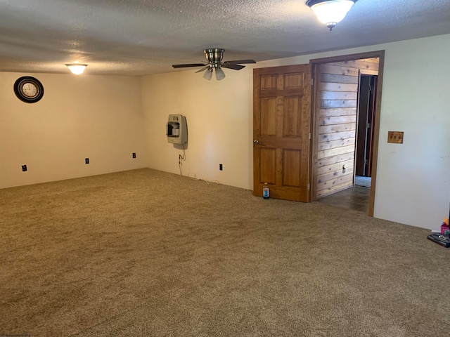 empty room with dark colored carpet, a textured ceiling, heating unit, and ceiling fan