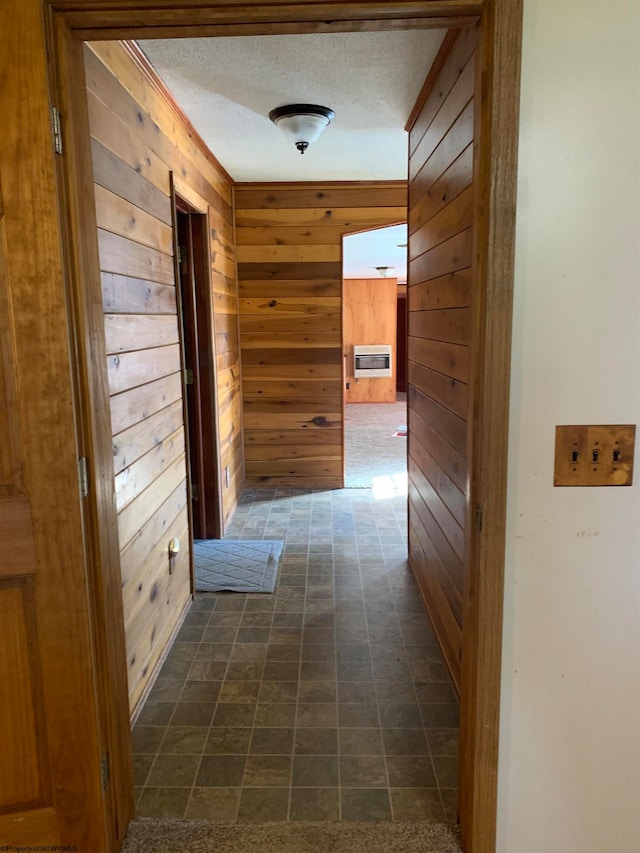 hall with a textured ceiling and wood walls